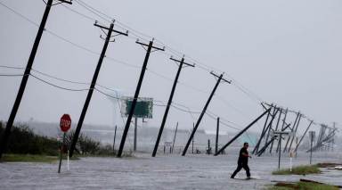 A man walks through floods waters after surveying his property which was hit by Hurricane Harvey in Rockport, Texas