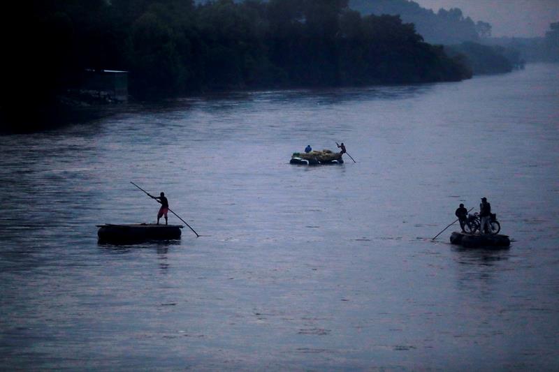Migrantes hondureños cruzan en balsa el río fronterizo de Guatemala y México